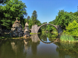 eine halbkreisförmige Steinbrücke an Orgelsteinen über einem See